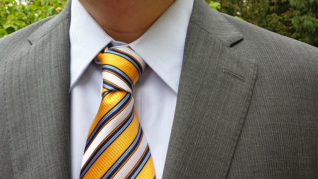 黄色系のストライプネクタイをスーツに合わせて着こなしている男性